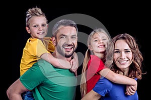 Happy family in colorful t-shirts hugging and smiling at camera