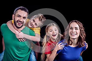 Happy family in colorful t-shirts hugging and smiling at camera