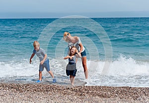 Happy family concept. attractive mother and little cute daughter and son having fun together on the beach