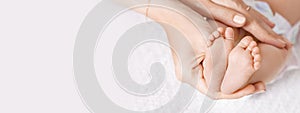 Happy Family concept. Beautiful conceptual image of Maternity. Baby feet in mother hands closeup. Mom and her Child. Banner. Copy