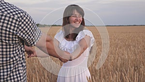 Happy family concept. beautiful girl holds her boyfriend`s ruic. hand in hand. lovers man and woman travel in field