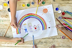 Happy family concept. Co-creation. Children hands draw on a sheet of paper: father, mother, boy and girl hold hands against photo