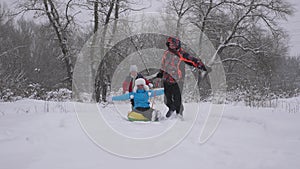 Happy family concept. Family plays in the winter park on Christmas holidays. Dad and daughter sled their mom in the