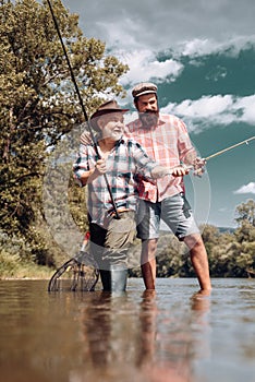 Happy family concept - father and son together. Fly fishing. Generations ages: grandfather and father. Generations men.