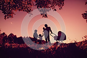 Happy family concept- silhouette of father with tree kids at sunset sky