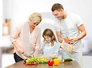 Happy family cooking vegetable salad for dinner