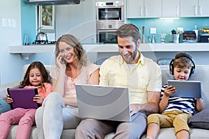 Happy family on the couch together using devices