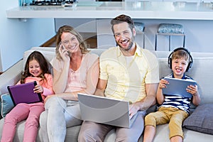 Happy family on the couch together using devices