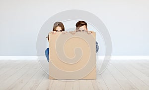 Happy family couple with cardboard poster on blank wall