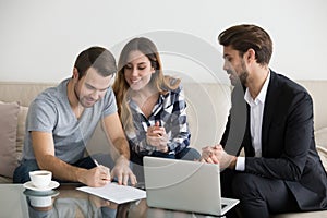 Happy couple renters or tenants sign rental contract meeting realtor photo