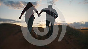 happy family couple and dog runs hands jumping up for joy at sunset on a hilltop and jumps. concept of team business