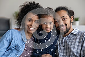 Happy family couple holding adorable little daughter child in arms