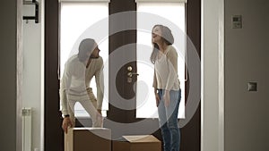Happy family couple holding boxes opening door entering new house