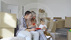 Happy family couple with kid son relaxing on couch on moving day in new home.