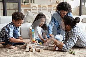 Happy family couple and little sibling kids constructing toy castle