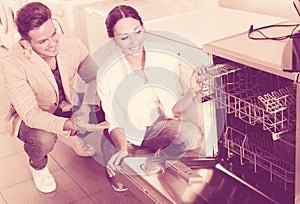 Happy family couple looking at dishwashers in store