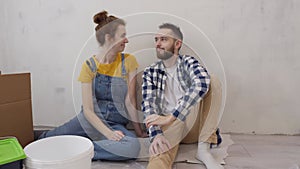 Happy family couple making hand heart looking on each other during apartment redecoration.