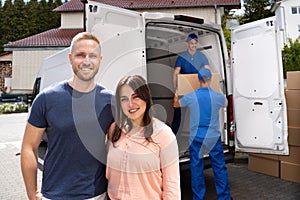 Happy Family Couple And Movers Unload Boxes