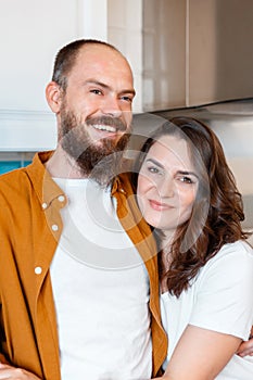Happy family couple portrait husband and wife in kitchen. Couple of young middle aged man and woman. Young Smiling bald