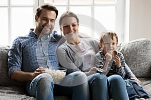 Happy family couple with preschooler son kid watching movie