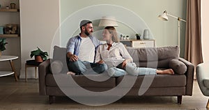 Happy family couple relax at home cuddle talk on sofa