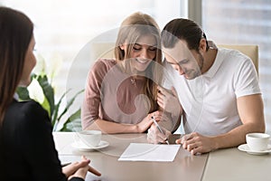 Happy family couple signing document, taking out bank loan, insu