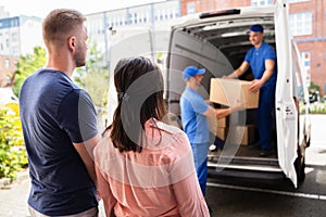 Happy Family Couple Watching Movers Unload Boxes