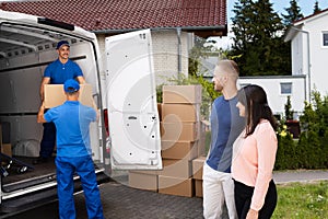 Happy Family Couple Watching Movers Unload Boxes