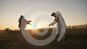 A happy family crowd together runs through a wheat field at sunset. Dad mom and children in the park have fun in nature