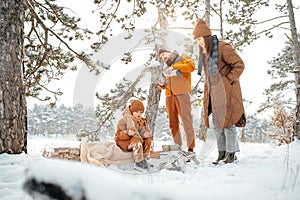 Happy family with cups of hot tea spending time together in winter forest