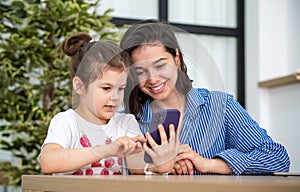 Happy family, cute little kid, daughter with mom, laughing, using smart phone, watching funny video on social media app, taking