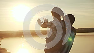 Happy family dad and daughter by the sea at sunset silhouette. father and child kid reach out to the sun. kid a dream