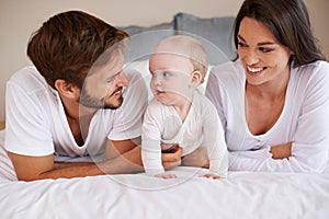 Happy family, dad and mom with baby on bed for love, care and quality time together at home. Mother, father and cute