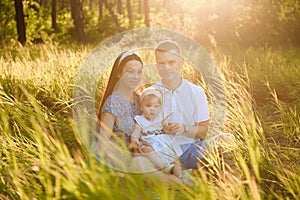 Happy family dad, mom playing in the fresh air on the field watching the beautiful emotional sunset in the backlight