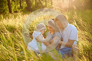 Happy family dad, mom playing in the fresh air on the field watching the beautiful emotional sunset in the backlight