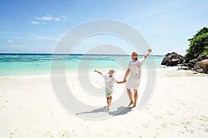 Happy family , dad and son, having fun together at the tropical beach, playing and looking at the blue sea and sky. Summer vibes.