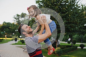 Happy family Dad throws child daughter up on a walk in park