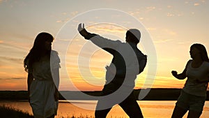 Happy family dancing on the beach. Party by lake, children dancing. Happy girls dancing on beach. Slow motion. Beautiful