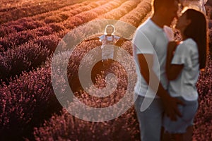 happy family day. young father, mother and child daughter are having fun together in the lavender field on sunset. happy