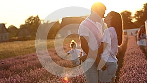 happy family day. young father, mother and child daughter are having fun together in the lavender field on sunset. happy