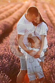 happy family day. young father, mother and child daughter are hugging in the lavender field in sunset light. happy
