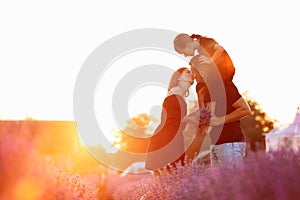 happy family day. Young mother and father carrying on shoulders daughter in lavender field on sunset. Dad, mom and child