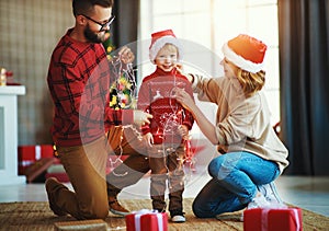 Happy family decorate Christmas tree, parents play with child son with garlands photo
