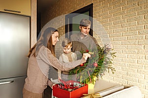 Happy family decorating a Christmas fir branches.