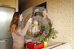 Happy family decorating a Christmas fir branches.