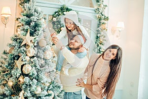Happy family decorating a Christmas tree with boubles in the living-room