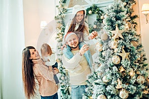 Happy family decorating a Christmas tree with boubles in the living-room