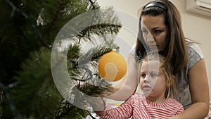 Happy family decorating a Christmas tree with boubles in the living-room