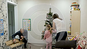 Happy family decorating a Christmas tree with boubles in the living-room