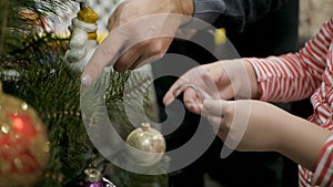 Happy family decorating a Christmas tree with boubles in the living-room